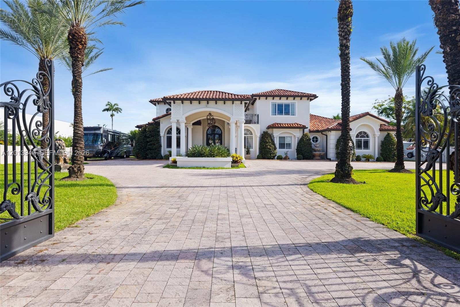 A large Mediterranean-style house features a paved driveway, arched entryway, and ornate iron gates — 9861 NW 135th St, Hialeah Gardens FL 33018, HIALEAH GARDENS, FL