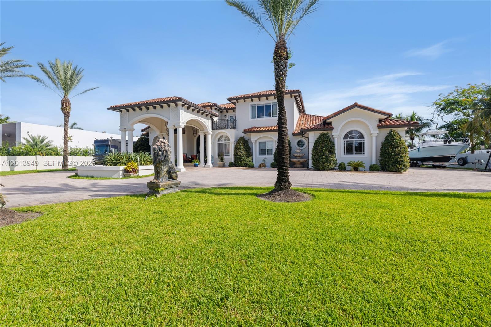 A two-story Mediterranean-style house features a large porte-cochère, a paved driveway, and a front lawn — 9861 NW 135th St, Hialeah Gardens FL 33018, HIALEAH GARDENS, FL