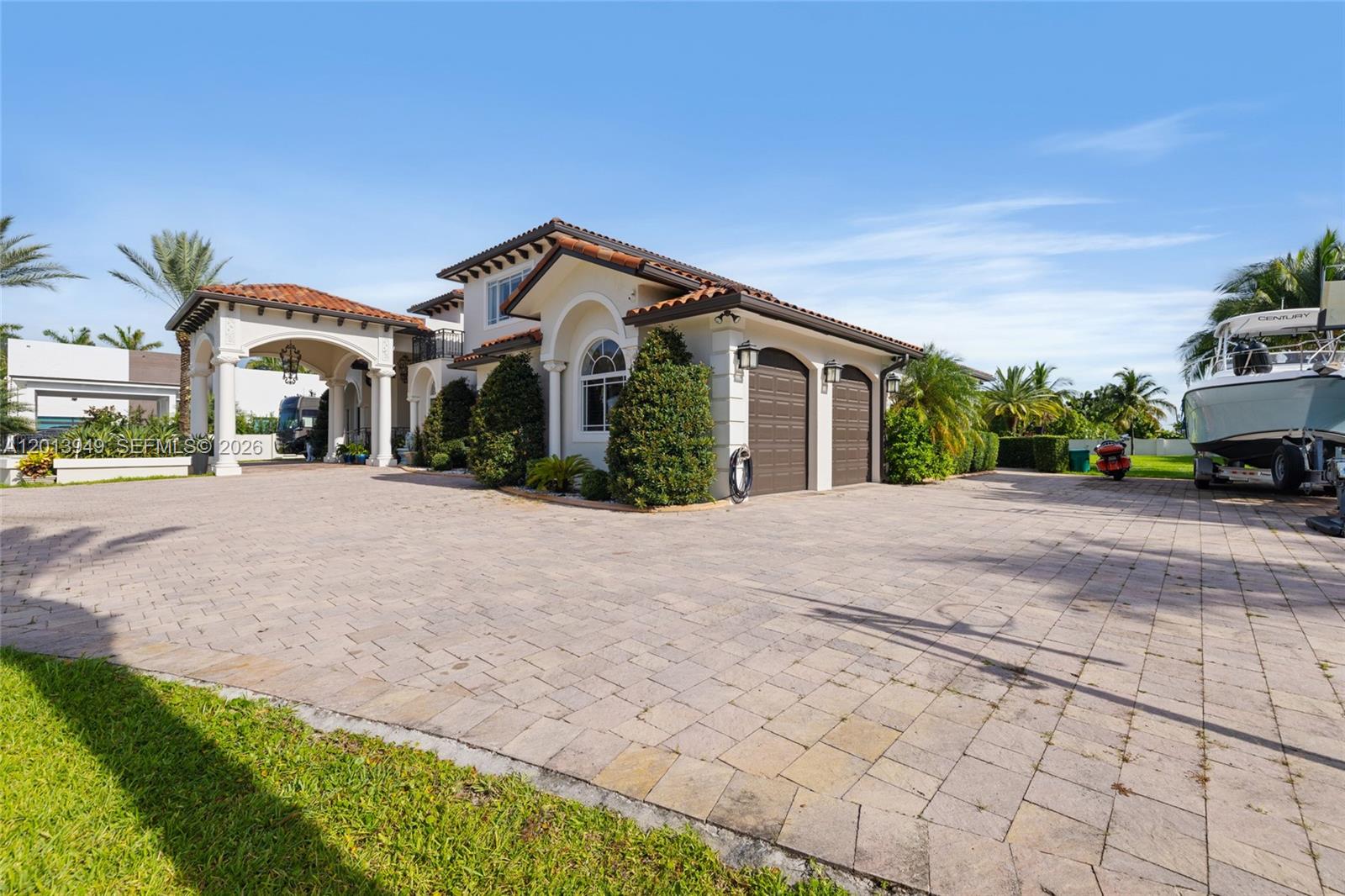 A paved driveway leads to a house with a covered entryway and two-car garage — 9861 NW 135th St, Hialeah Gardens FL 33018, HIALEAH GARDENS, FL