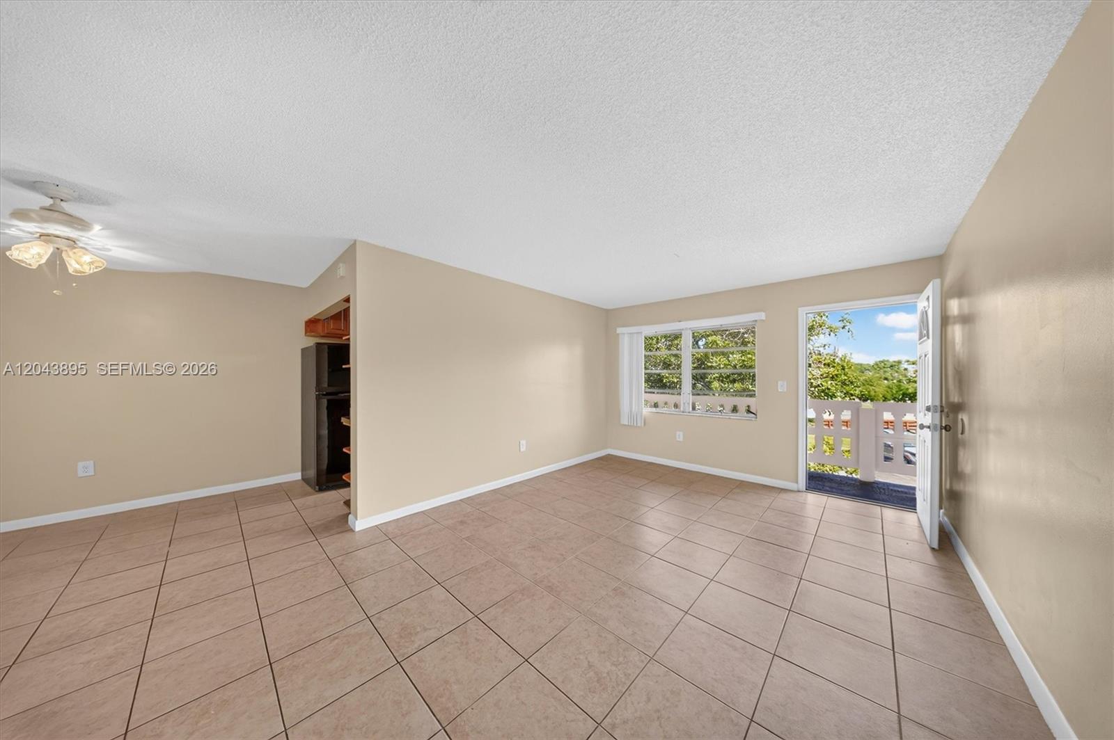 An empty room features beige walls, tiled floors, a ceiling fan, and an open door — 20311 NE 2nd Ave # 21, Miami FL 33179, MIAMI, FL
