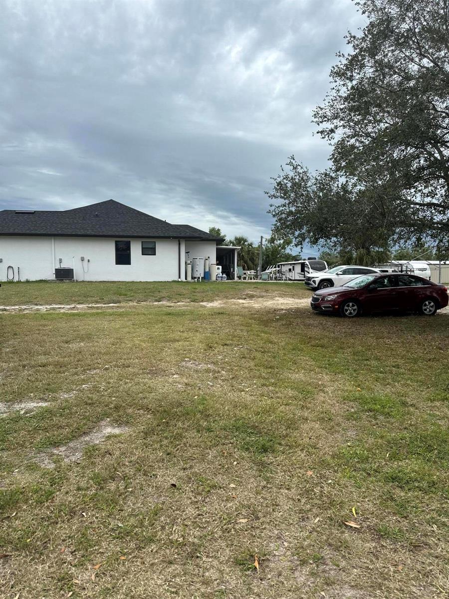 A grassy lot sits in front of a white house with a dark roof — 3401 Sand Road, Cape Coral FL 33993, CAPE CORAL, FL