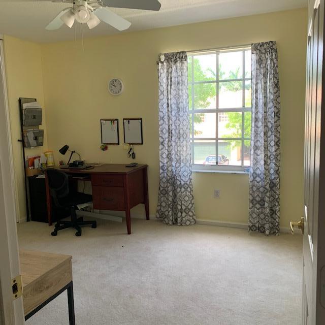 A home office with a wooden desk, chair, wall-mounted organizers, and a window with curtains — 9019 Alexandra Circle, Wellington FL 33414, WELLINGTON, FL