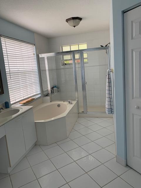 A bathroom features a white soaking tub, a glass-enclosed shower, and white tile flooring — 9019 Alexandra Circle, Wellington FL 33414, WELLINGTON, FL