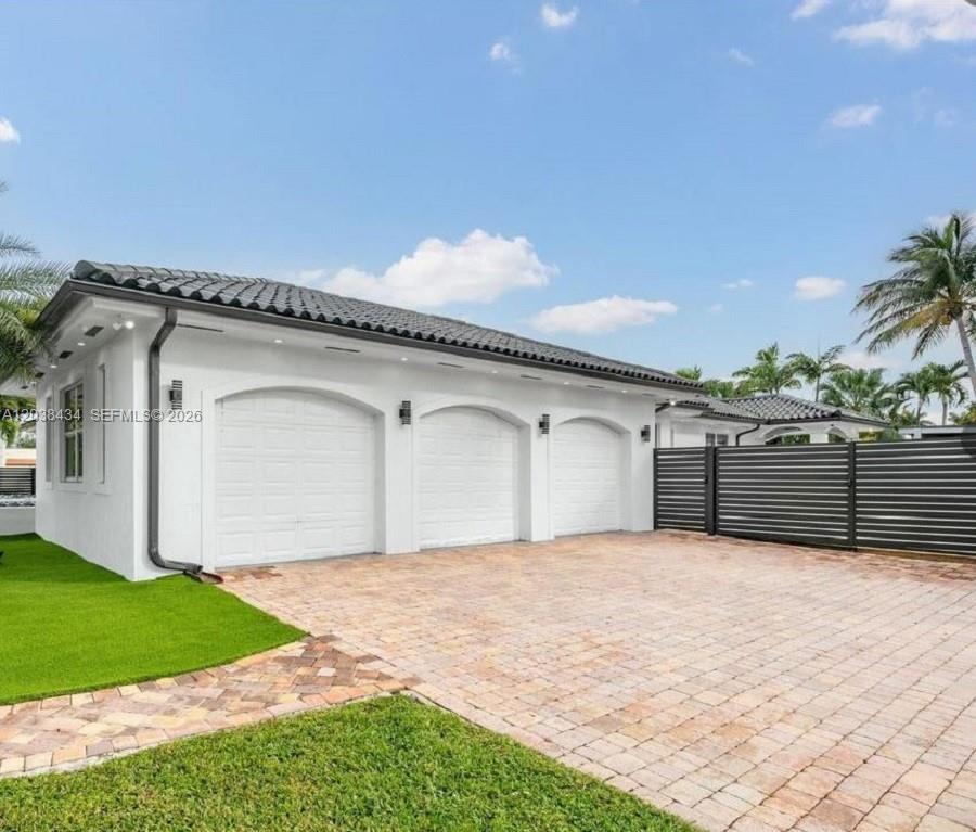 A white three-car garage with arched openings and a brick paver driveway — 11390 SW 30th St, Miami FL 33165, MIAMI, FL