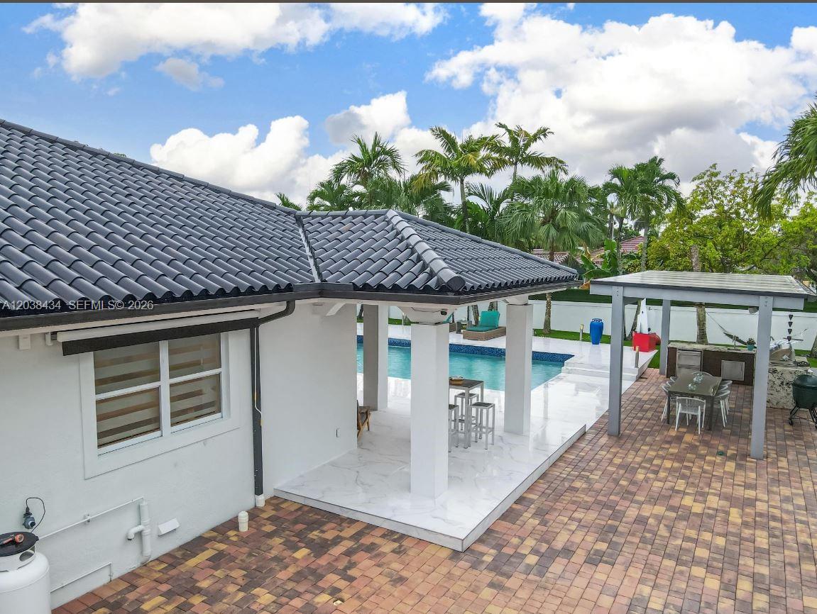 A white house exterior features a covered patio, swimming pool, and a paved outdoor area — 11390 SW 30th St, Miami FL 33165, MIAMI, FL