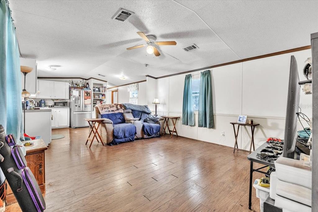 A living room with wood-look flooring, a ceiling fan, and an open kitchen in back — 1169 LAFAYETTE STREET, PUNTA GORDA, FL