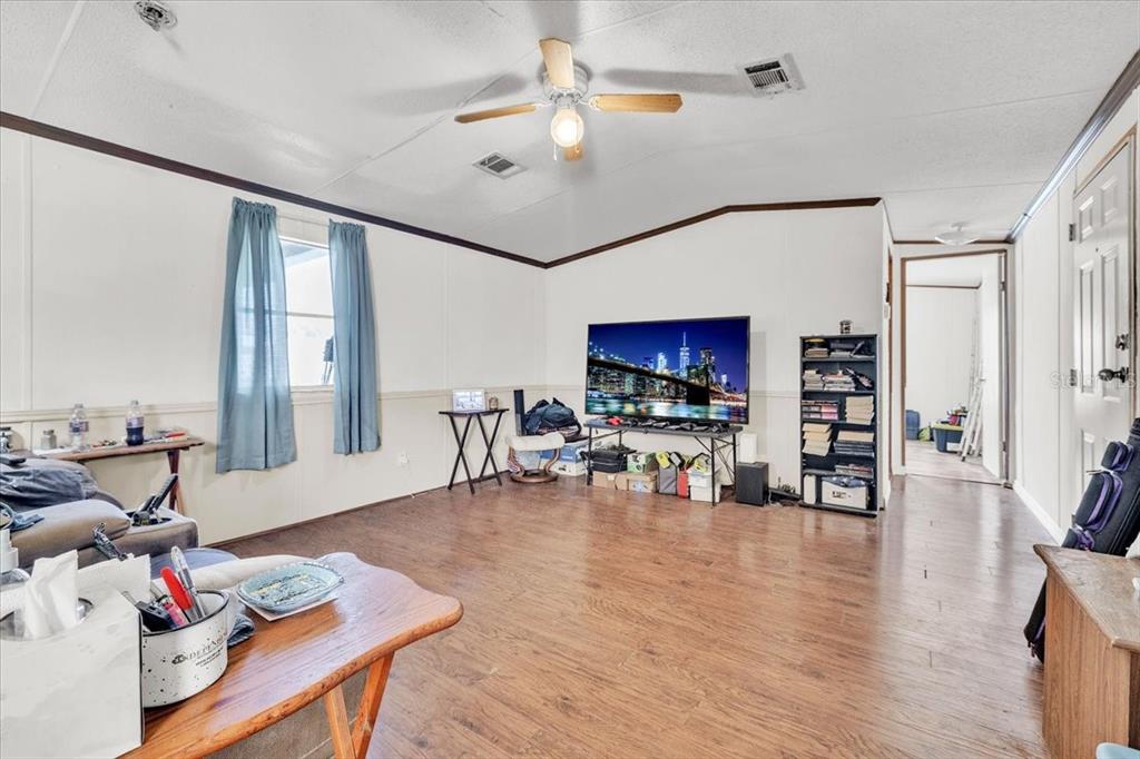 A living room features wood-look flooring, white walls, a ceiling fan, and a television stand — 1169 LAFAYETTE STREET, PUNTA GORDA, FL
