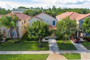 An aerial view shows three suburban houses with tiled roofs and driveways in a neighborhood — 8985 CUBAN PALM RD. ROAD, KISSIMMEE, FL