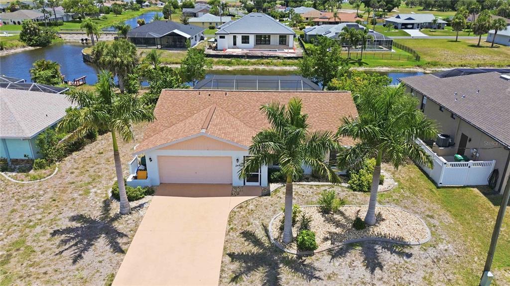 An aerial view shows a single-story house with a tan roof and a concrete driveway — 244 MARK TWAIN LANE, ROTONDA WEST, FL