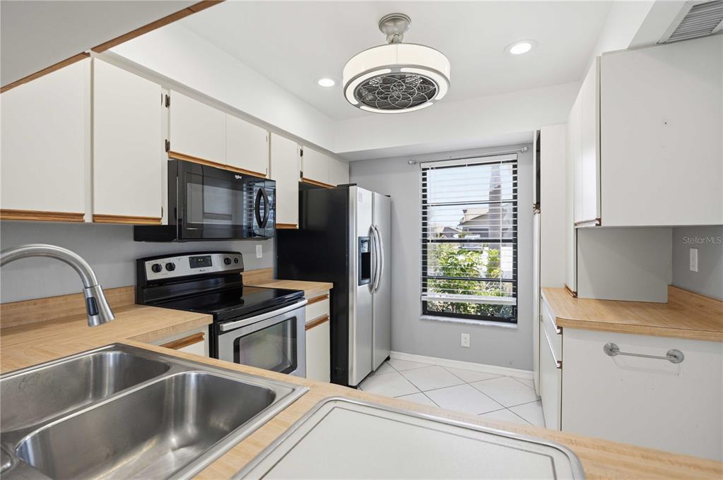 A kitchen features white cabinets, laminate countertops, stainless steel appliances, and a ceiling fan light — 244 MARK TWAIN LANE, ROTONDA WEST, FL