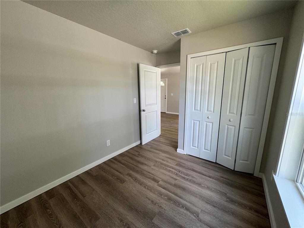 A bedroom with light gray walls, wood-look flooring, a white door, and a bi-fold closet — 343 N MAIN AVENUE, GROVELAND, FL