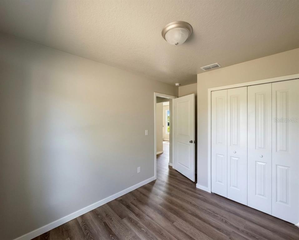 A bedroom with light gray walls, wood-look flooring, a ceiling light, and white closet doors — 343 N MAIN AVENUE, GROVELAND, FL