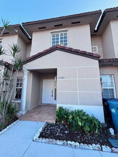 The exterior of a two-story townhouse features a beige stucco facade and a front entrance — 13726 SW 171st Ln, Miami FL 33177, MIAMI, FL