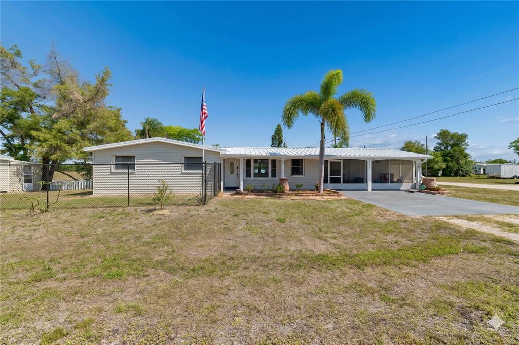 A single-story house with light siding, a metal roof, and a palm tree in front — 1130 SWEENEY DRIVE, RUSKIN, FL
