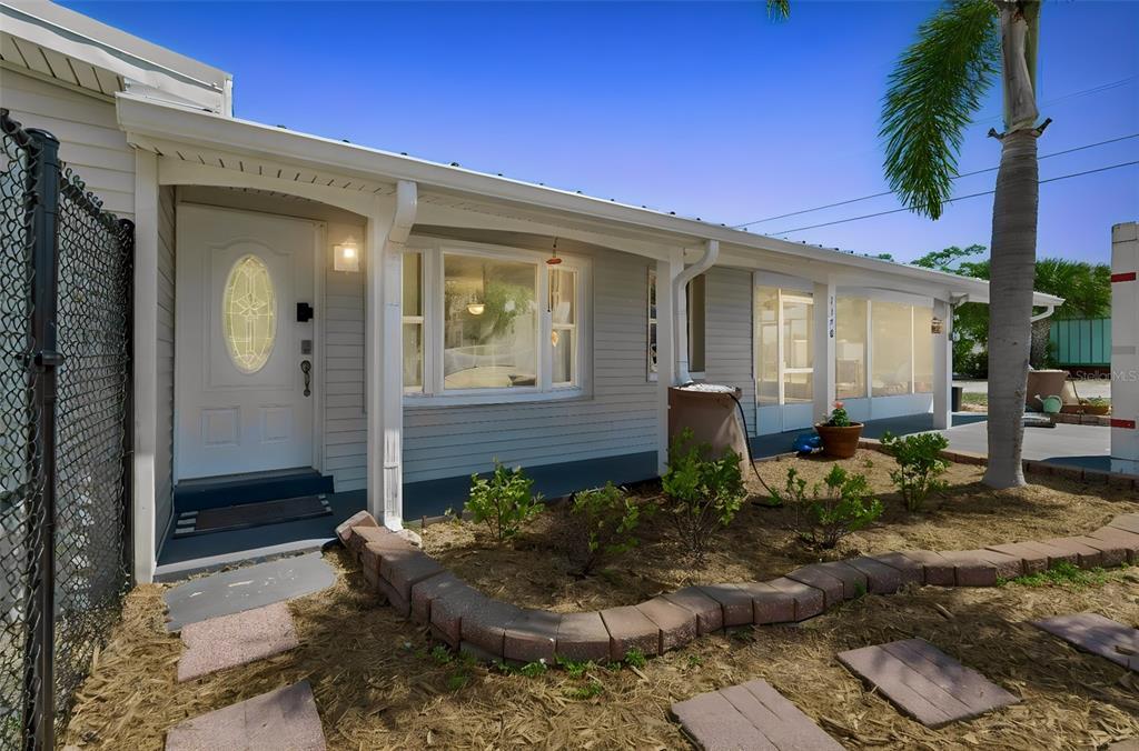 A light gray house exterior features a white front door, bay window, and landscaped yard — 1130 SWEENEY DRIVE, RUSKIN, FL