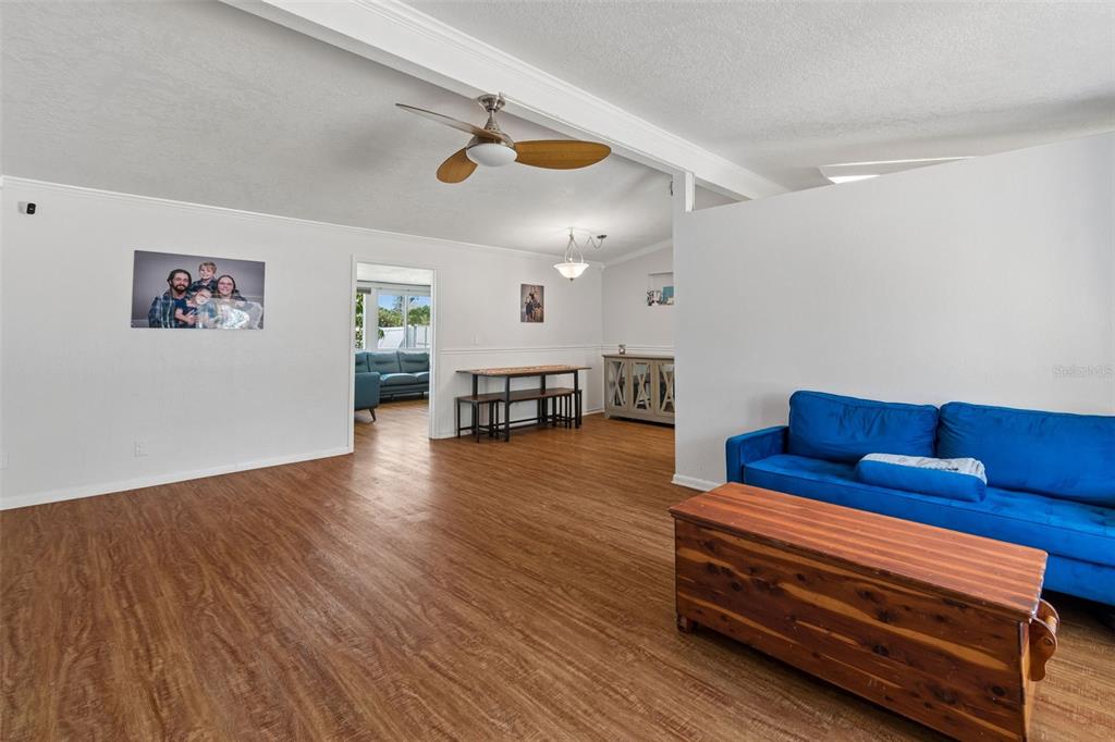 A living room with wood-look flooring, a blue sofa, and a wooden coffee table — 1130 SWEENEY DRIVE, RUSKIN, FL