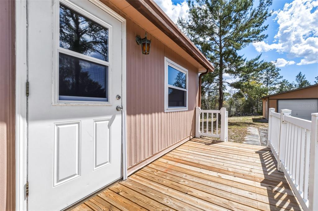 A wooden deck with a white railing sits outside a house with tan siding — 5590 W MCDOWELL LANE, DUNNELLON, FL