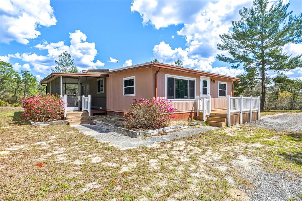 A single-story house with tan siding, a screened porch, and a wooden deck — 5590 W MCDOWELL LANE, DUNNELLON, FL
