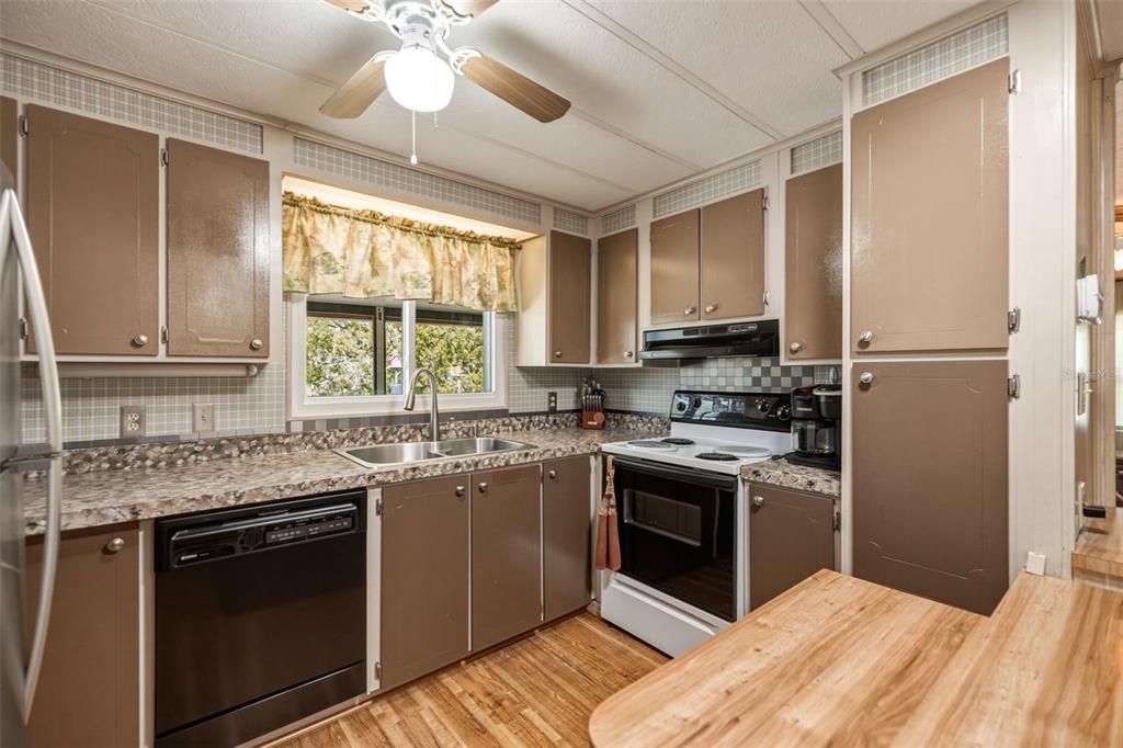 A kitchen features brown cabinets, laminate countertops, a white stove, and a black dishwasher — 5590 W MCDOWELL LANE, DUNNELLON, FL