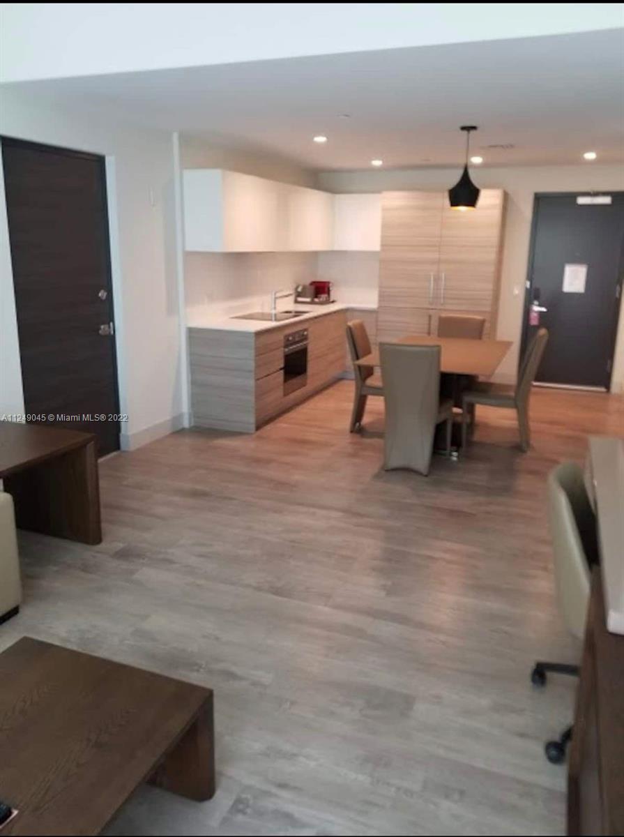 This open-concept kitchen and dining area features light wood cabinetry, white countertops, and wood-look flooring — 777 N Ocean Dr # N323, Hollywood FL 33019, HOLLYWOOD, FL