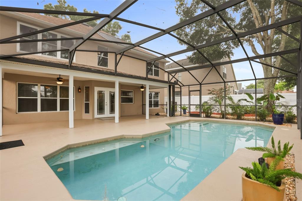 A screened-in patio features a swimming pool and a view of the two-story house exterior — 1800 PINE BAY DRIVE, LAKE MARY, FL