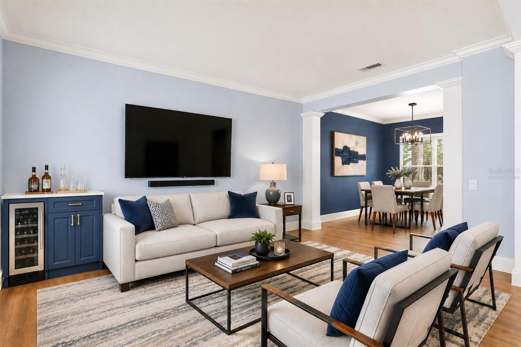 A living room with a light blue wall, a sofa, two armchairs, and a dining area — 1800 PINE BAY DRIVE, LAKE MARY, FL