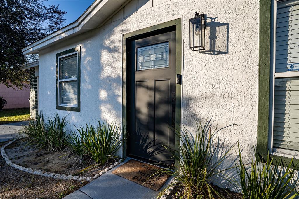 A front exterior view showing a dark door, a window, and a light fixture — 315 LAUDERDALE COURT, KISSIMMEE, FL