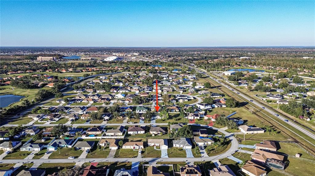 An aerial view of a suburban neighborhood with a red arrow pointing to a house — 315 LAUDERDALE COURT, KISSIMMEE, FL