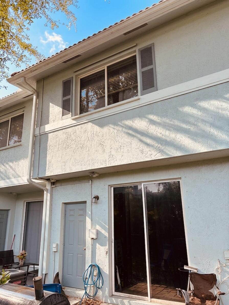 The exterior of a two-story light blue stucco building features a sliding glass door — 3731 Sonoma Drive, Riviera Beach FL 33404, RIVIERA BEACH, FL