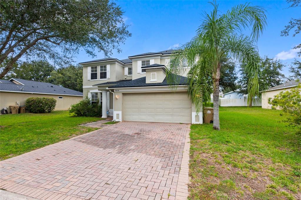 A two-story house with a brick paver driveway, a two-car garage, and a palm tree — 15319 MONTAUK LANE, CLERMONT, FL