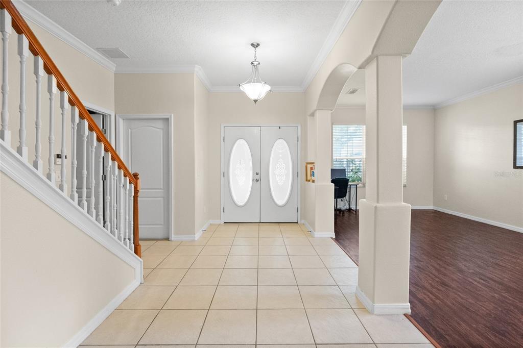 A foyer with tile flooring, a staircase, and double front doors leading to a room — 15319 MONTAUK LANE, CLERMONT, FL