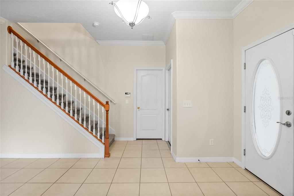 An entryway features a tiled floor, a staircase with a wooden railing, and a front door — 15319 MONTAUK LANE, CLERMONT, FL