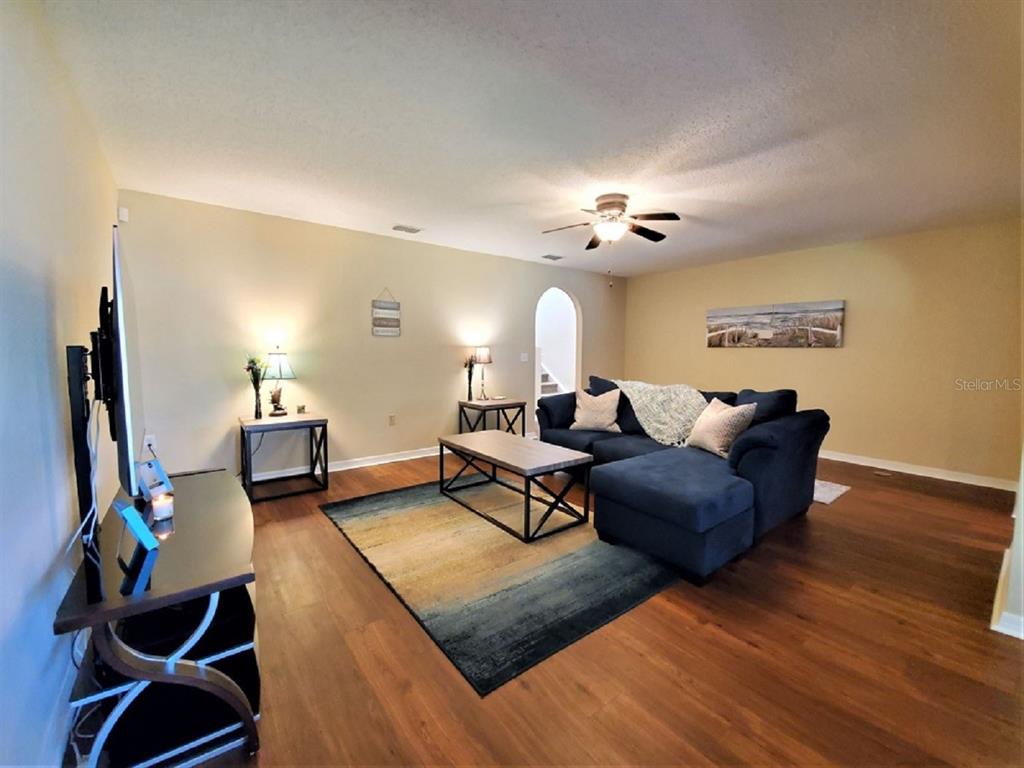 A living room features a blue sectional sofa, a coffee table, and wood-look flooring — 9870 ASHBURN LAKE DRIVE, TAMPA, FL