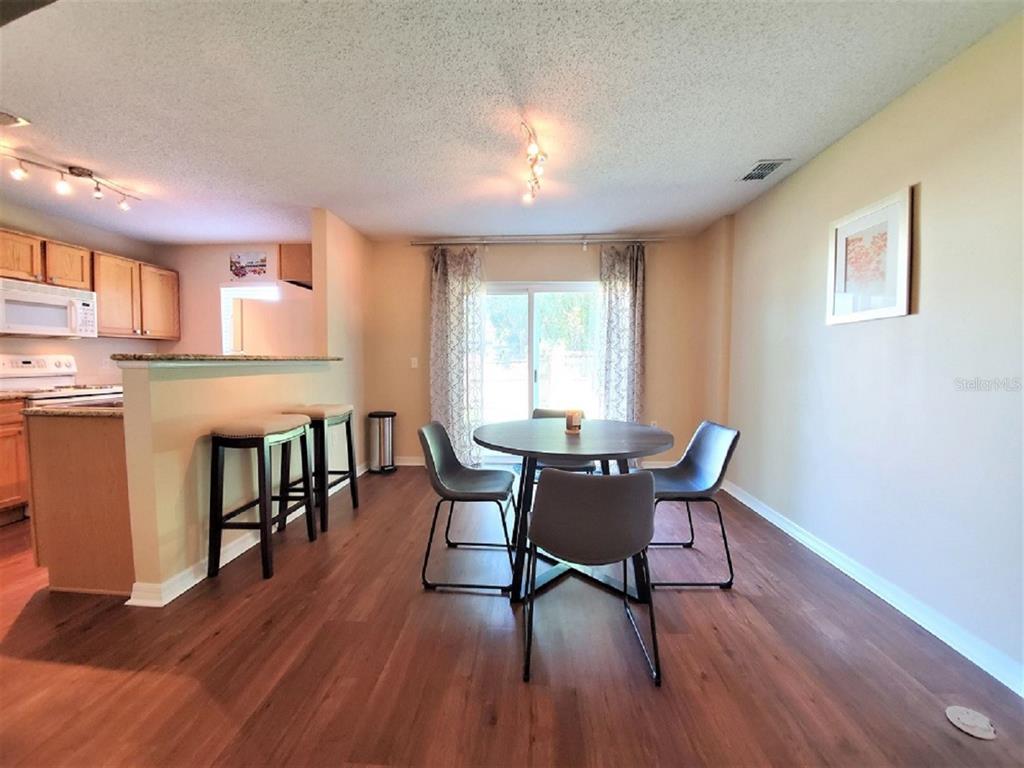 A dining area with a round table and chairs adjacent to an open kitchen — 9870 ASHBURN LAKE DRIVE, TAMPA, FL