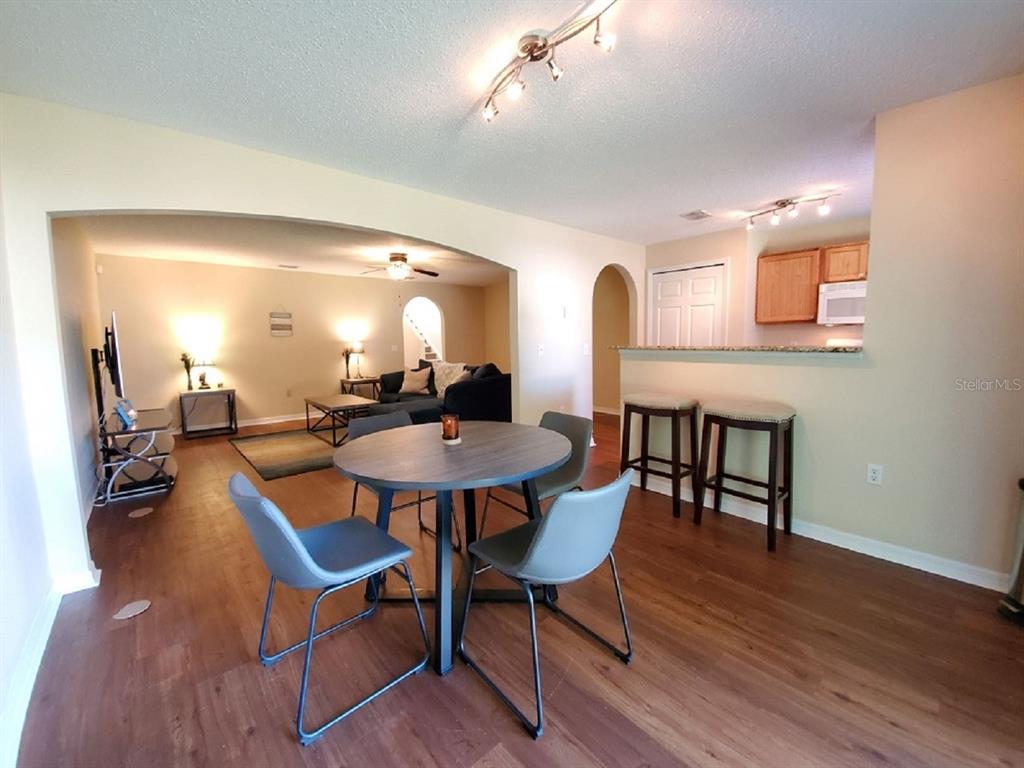 A dining area with a round table and chairs opens into a living room — 9870 ASHBURN LAKE DRIVE, TAMPA, FL