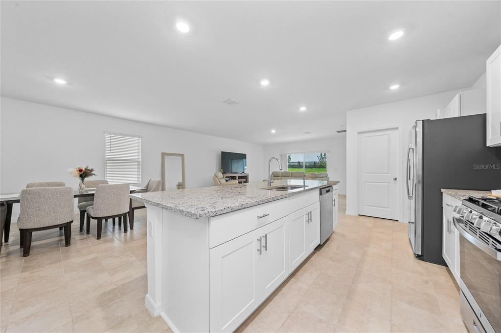 A kitchen with white cabinets, granite countertops, and an island overlooks an open living area — 7396 CAPSTONE DRIVE, GROVELAND, FL