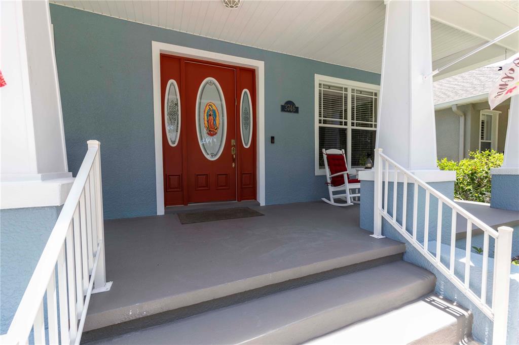 A blue house exterior features a red front door with glass inserts and a porch — 3746 DOGTROT STREET, NEW PORT RICHEY, FL
