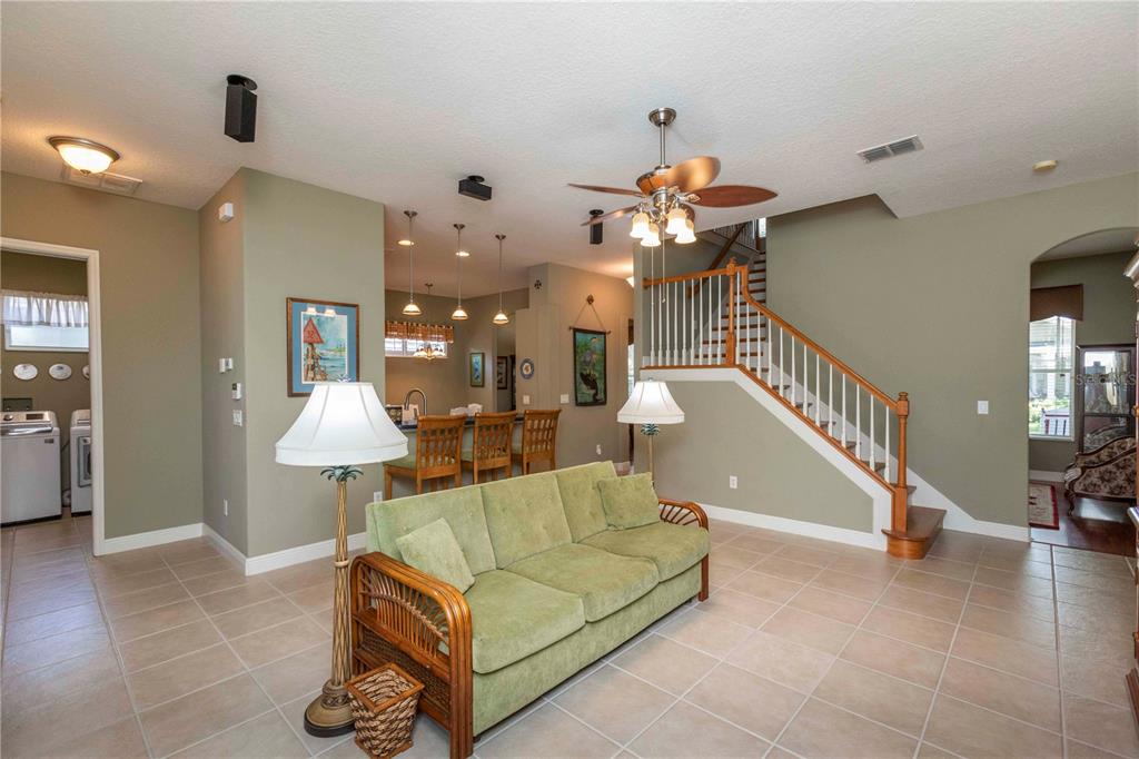 A living room with a green sofa, tile floors, and a staircase leading upstairs — 3746 DOGTROT STREET, NEW PORT RICHEY, FL