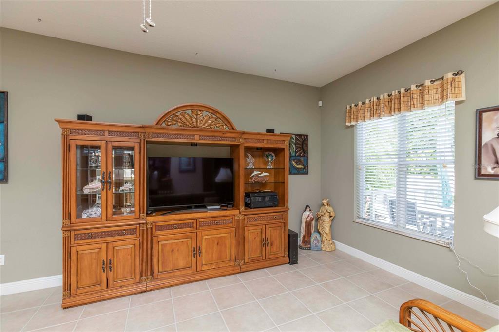 A living room features a large wooden entertainment center, tile flooring, and a window with blinds — 3746 DOGTROT STREET, NEW PORT RICHEY, FL