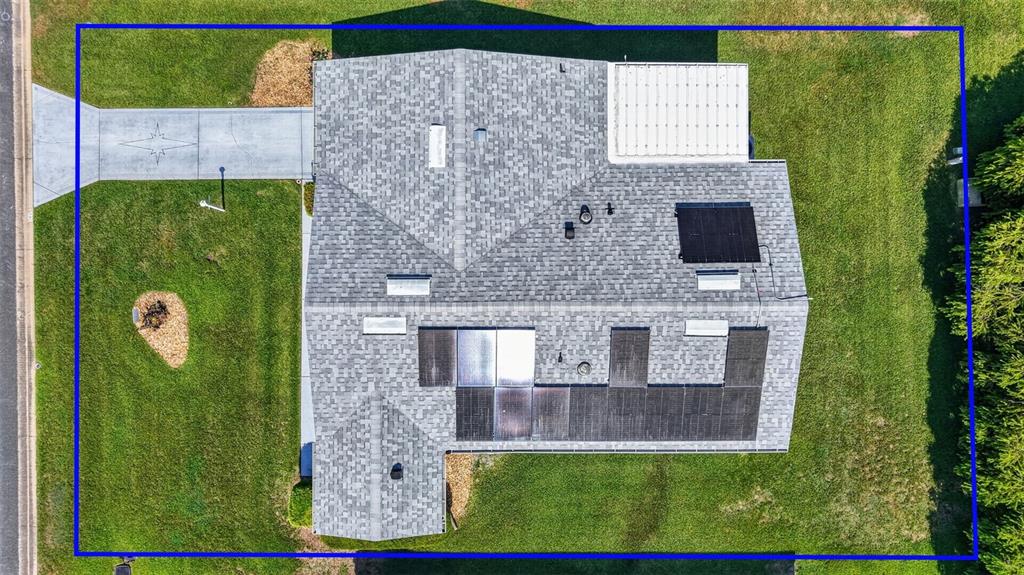 An aerial view shows a house with a shingled roof, solar panels, and a driveway — 1231 ZAPATA PLACE, LADY LAKE, FL