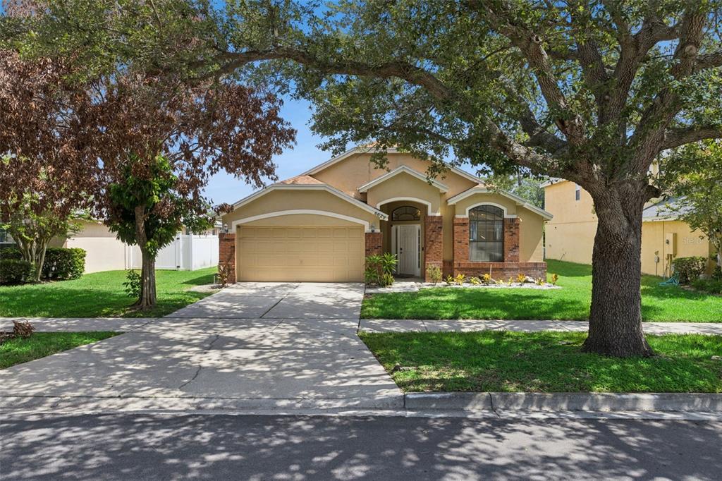 A single-story house with a tan stucco exterior, brick accents, and a two-car garage — 6629 WINDER OAKS BOULEVARD, ORLANDO, FL