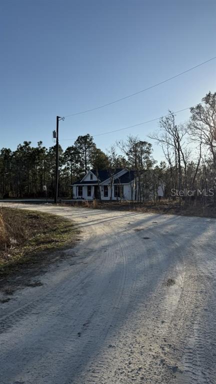 A white house with a dark roof sits at the end of a dirt road — 0 NE 151ST AVENUE, WILLISTON, FL