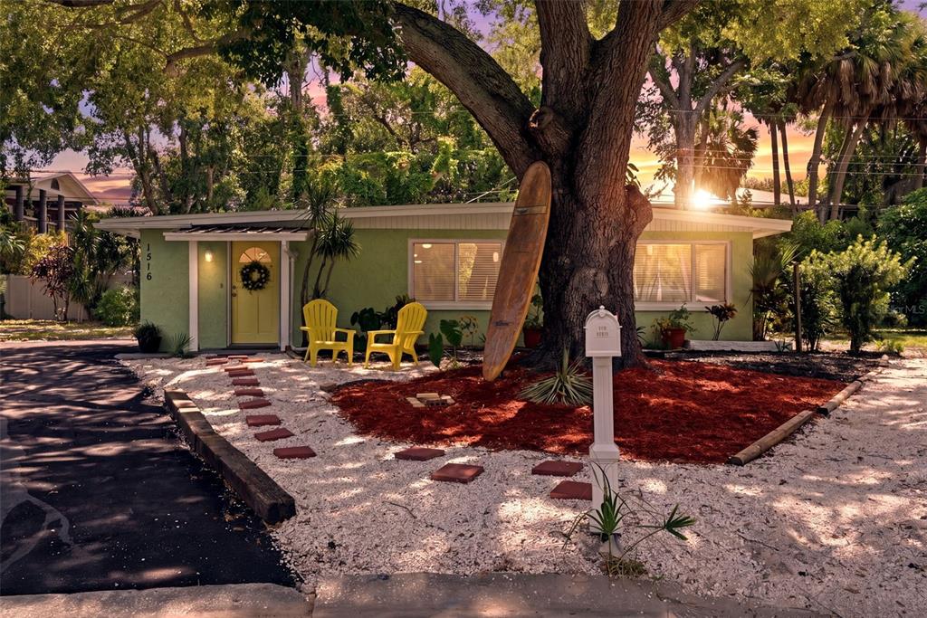 A light green house with a yellow door, two yellow chairs, and a surfboard tree — 1516 ADELE PLACE, LARGO, FL