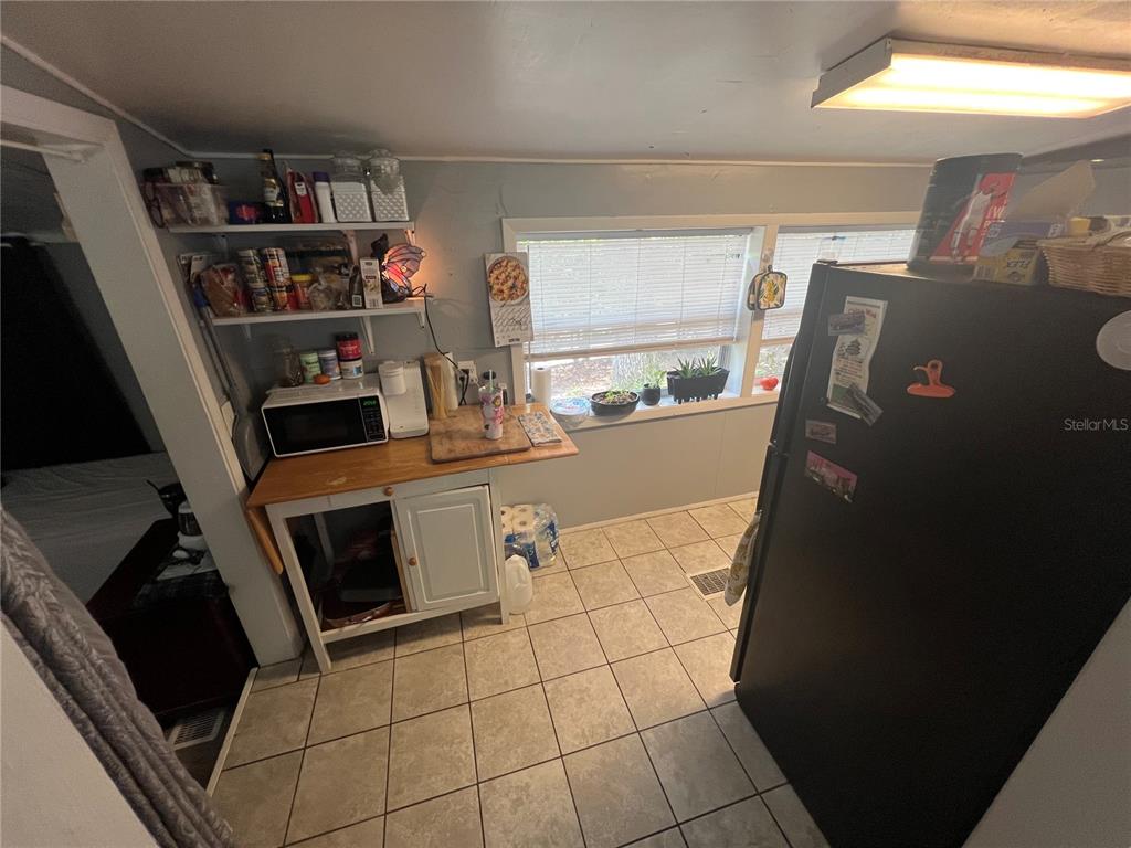 A kitchen features tile flooring, a black refrigerator, a microwave, and open shelving — 6724 COUNTY ROAD 214, KEYSTONE HEIGHTS, FL