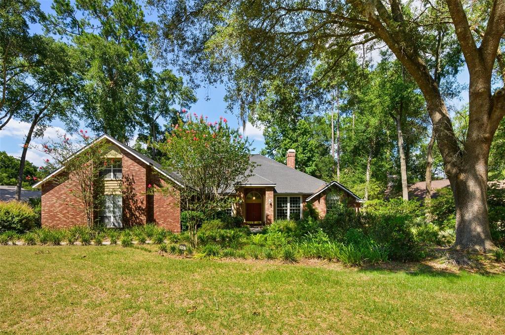 A brick house with a dark shingled roof sits behind a lawn and mature trees — 3627 NW 33RD TERRACE, GAINESVILLE, FL