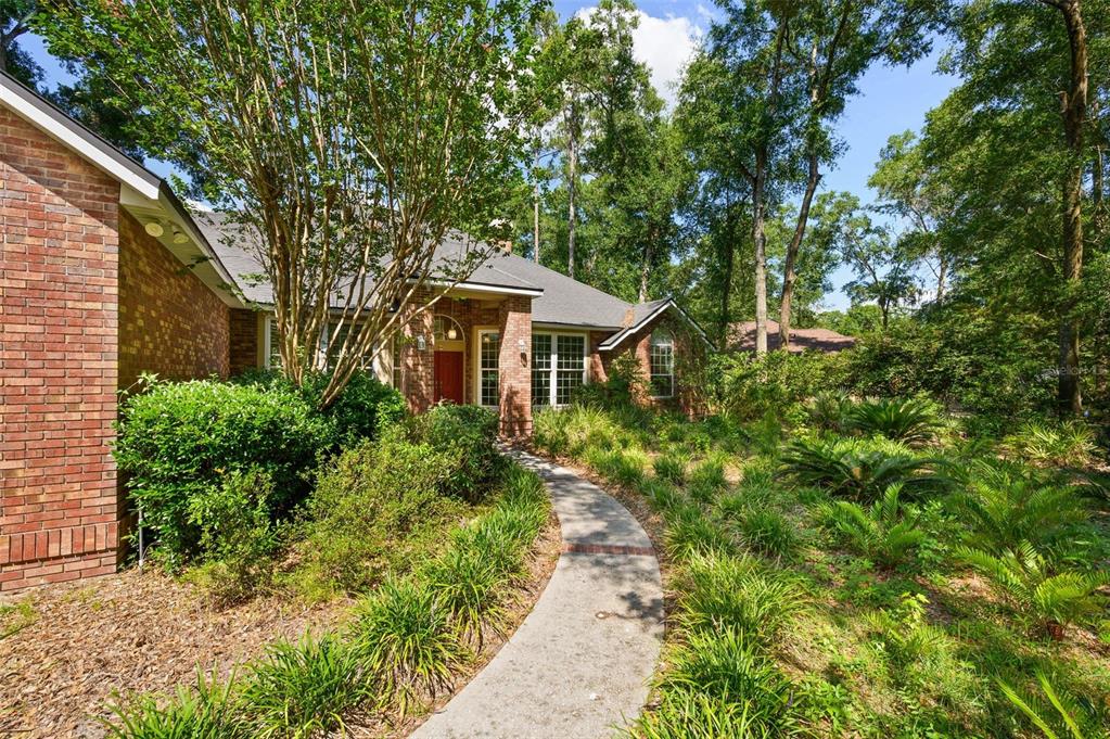A brick house with a curved concrete walkway leading to a red front door — 3627 NW 33RD TERRACE, GAINESVILLE, FL