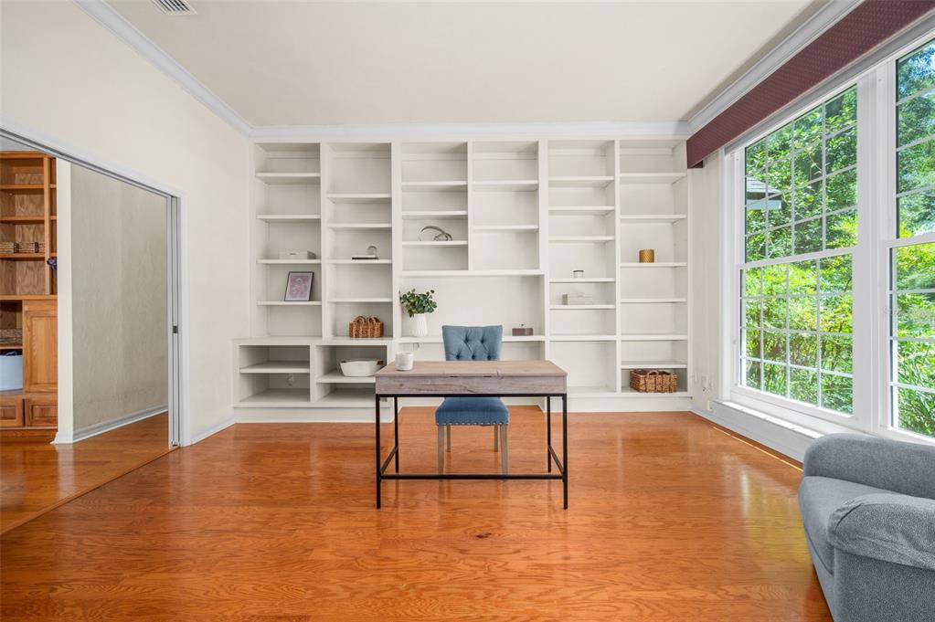 A home office features hardwood floors, a central desk with a blue chair, and built-in shelving — 3627 NW 33RD TERRACE, GAINESVILLE, FL