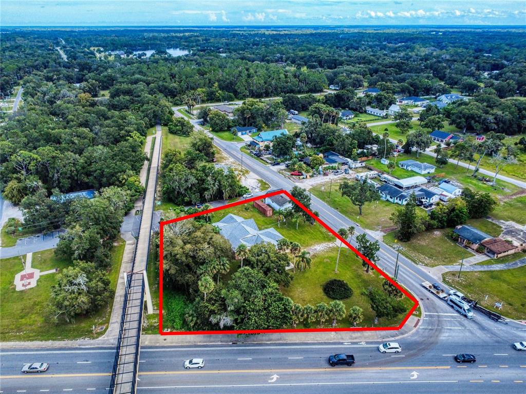 An aerial view shows a house on a corner lot bordered by a road and walkway — 120 RAILROAD AVENUE, OSTEEN, FL