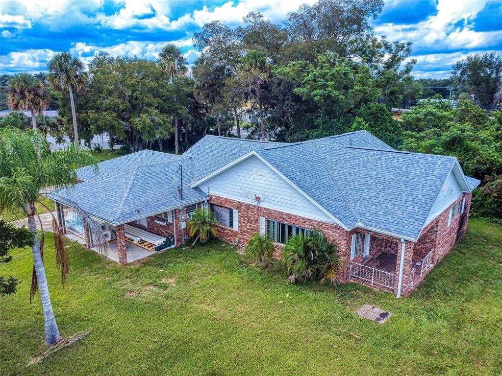 An aerial view of a brick house with a gray shingled roof and a lawn — 120 RAILROAD AVENUE, OSTEEN, FL