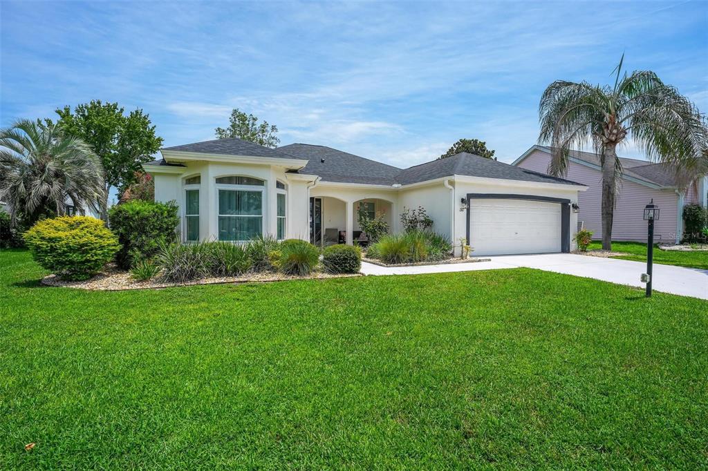 A single-story house with a white exterior, a two-car garage, and a front lawn — 1511 LAVACA LANE, LADY LAKE, FL